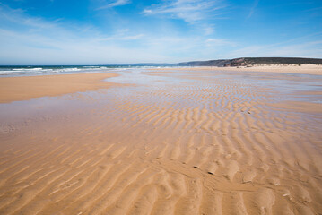coastal landscape Bordeira beach with rippled sand and cliff at the horizon