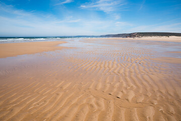 Fototapeta na wymiar coastal landscape Bordeira beach with rippled sand and cliff at the horizon
