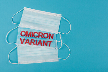 Top view of medical masks with omicron variant lettering on blue background.