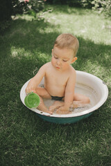 a child cools down in the heat in the summer in a basin in the backyard of the house