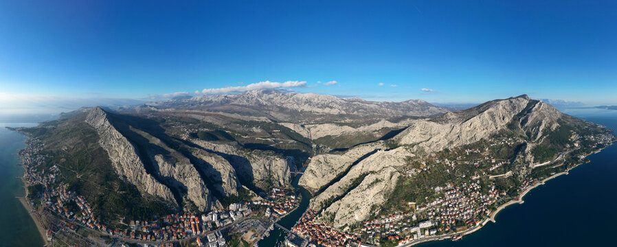 Aerial drone panorama view of Omis town in Croatia. Location is where the Cetina River meets the Adriatic Sea.  Beautiful city next to the mountains and the sea. Travel and holidays destination.