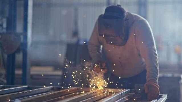 Professional welder works in a dark room with slow motion. Cinematic