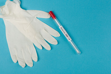 Top view of latex gloves near throat swab with omicron xbb lettering on blue background.