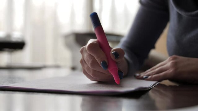 A woman highlights text in a document with a highlighter marker. Close-up of a felt-tip pen in female hands. Office worker works with documentation.