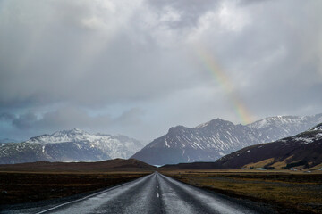 Straight road leading into Icelandic mountains under dramatic skies