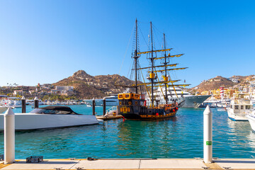 A replica of a pirate ship sits among sailboats and luxury yachts at the marina at Cabo San Lucas,...