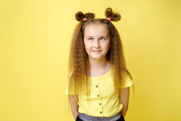 Cool cute girl with a trendy hairstyle in a yellow top on a yellow background with bright emotions