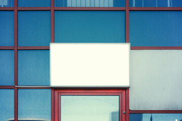 White blank mockup in steel frame fixed on glass building wall