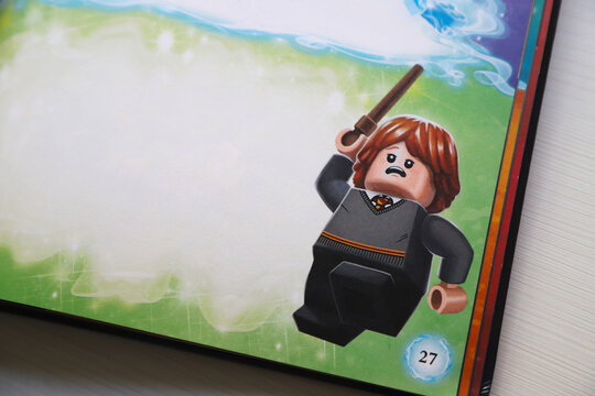  Ron Weasley for performing a spell with his wand. Book of Harry Potter with Lego characters. Banner. Poster. Empty space for text or birthday card. Toy doll. 