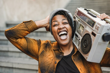Young african female street musician rapping in the city while holding vintage boombox