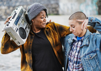 Young multiracial female street musicians rapping in the city - Focus on the african girl holding...