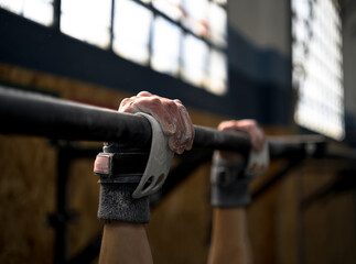 Girl holding on to the bar to do wide pull-ups.
