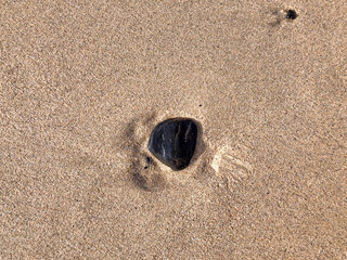 Fototapeta na wymiar black lava stone in the sand