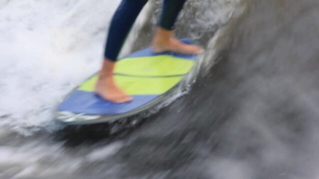 Wakesurfing sportsman in blue neoprene swimsuit performs stunts professionally at high speed on board among waves in sea closeup