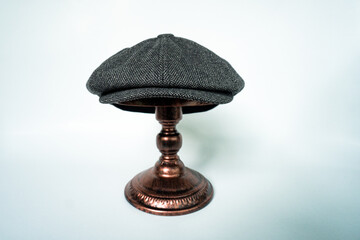 Detail of a classic eight-panel newsboy hat, in midnight dark herringbone tweed fabric set against...