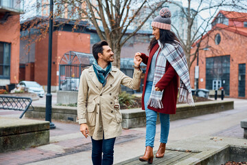 Happy couple holding hands and talking while walking outdoors.