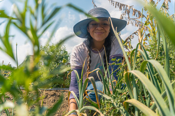 Happy young woman smiling at the camera while in her vegetable garden