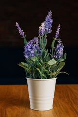 Vertical shot of some violet artificial lavender flowers standing on a wooden table.