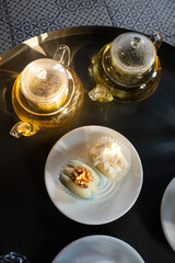 Green tea in transparent teapots, tea in a cup and macaroons on a plate