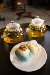 Green tea in transparent teapots, tea in a cup and macaroons on a plate