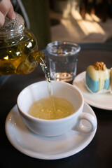 Green tea in transparent teapots, tea in a cup and macaroons on a plate