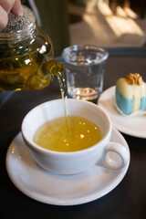 Green tea in transparent teapots, tea in a cup and macaroons on a plate
