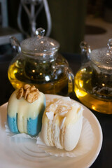 Green tea in transparent teapots, tea in a cup and macaroons on a plate