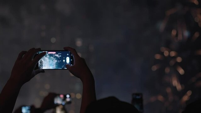 Silhouette Crowd of People Hands Recording Beautiful Fireworks Using Their Mobile Phones in Slow Motion