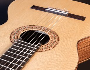 Fototapeta premium Classical guitar top isolated on black background with a beautiful mosaic rosette, view from the top side. Beautiful Brazilian wood - Pau Ferro on the back and spruce on the top. 