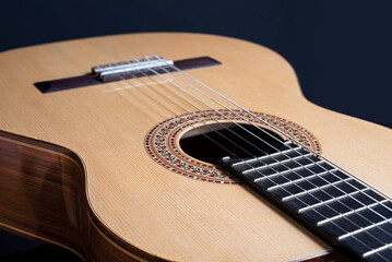 Fototapeta premium Classical guitar top isolated on black background with a beautiful mosaic rosette, view from the top side. Beautiful Brazilian wood - Pau Ferro on the back and spruce on the top. Classic acoustic guit