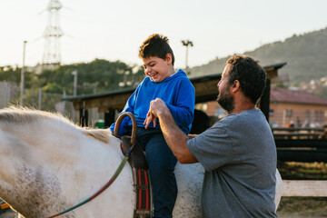 Smiley boy with cerebral palsy receiving equine therapy