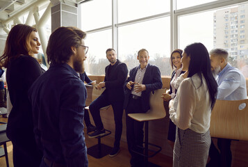 Informal conversation. Smiling office colleagues have pleasant conversation discussing work during...