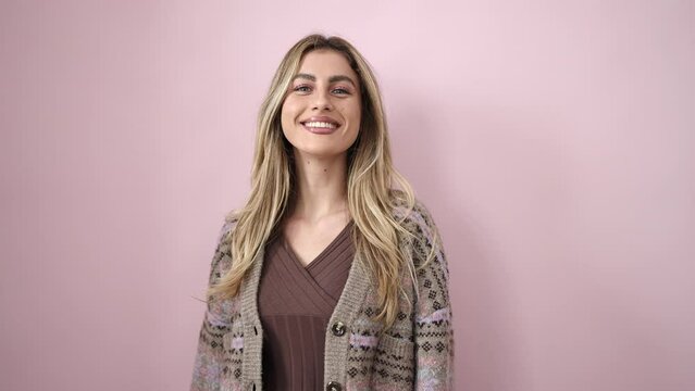 Young blonde woman smiling confident standing over isolated pink background