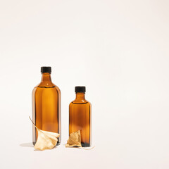 Ginkgo biloba essential extract in a bottle and golden leaves. Minimal neutral herbal or natural medicine arrangement. Ginkgo biloba.