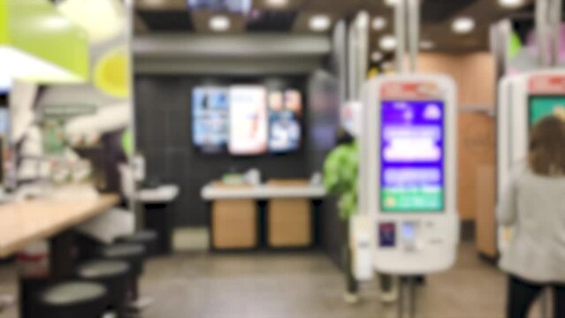 people visitors customers, a lot of people, in street clothes, make an order and wait for an electronic queue on screen order number in a fast food restaurant.blurry.concept background consumption.