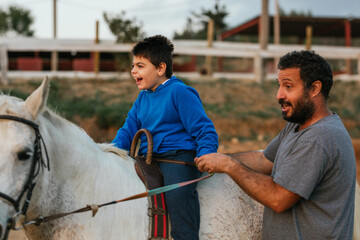 Happy boy with cerebral palsy on a horse