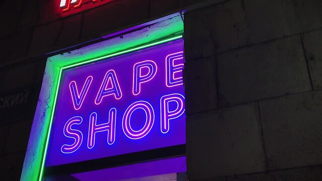 vape shop electronic cigarette neon colored window showcase sign lights glow up attracting customers on the street at night.concept vape shop.