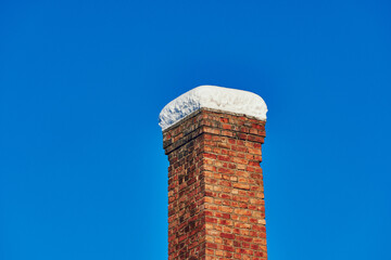 A red brick stone chimney in winter.