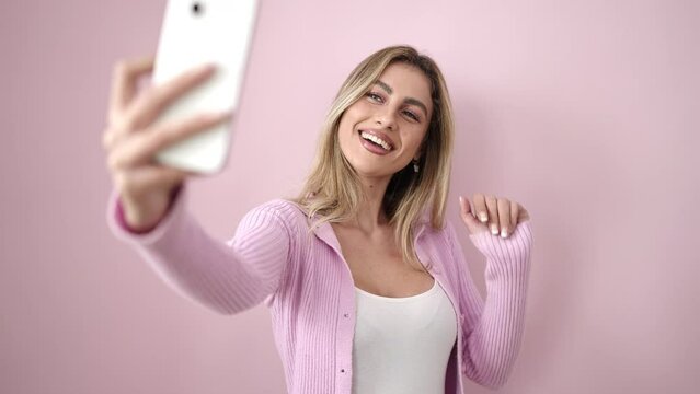 Young blonde woman smiling confident making selfie by smartphone over isolated pink background