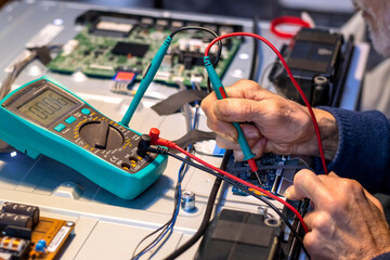 Close up of Technician measuring voltage electronic circuit board television, Service after sale fix electric equipment within insurance.