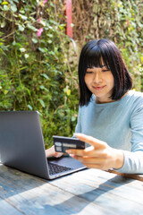 Young Asian woman using laptop for electronic banking 