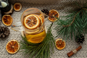 Green tea in a transparent, glass teapot, dried oranges and Christmas atmosphere, Christmas tree branches