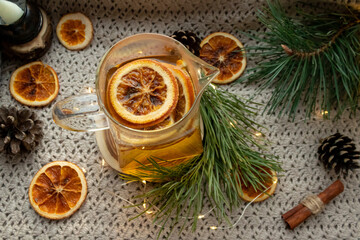 Obraz na płótnie Canvas Green tea in a transparent, glass teapot, dried oranges and Christmas atmosphere, Christmas tree branches