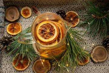Green tea in a transparent, glass teapot, dried oranges and Christmas atmosphere, Christmas tree branches