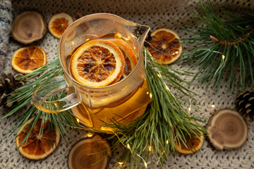 Green tea in a transparent, glass teapot. Dried oranges and Christmas tree branches