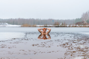 A man takes the ice bath in frozen lake, the icy water providing a refreshing and invigorating...