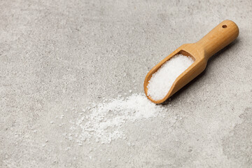 Coarse salt in a wooden spoon on a stone kitchen table.