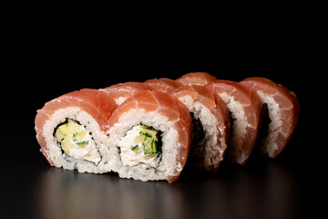 delicious Philadelphia sushi rolls with salmon, cucumber, avocado, cream cheese. On dark background.