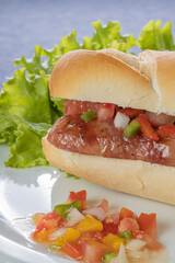 Detail of a choripan, typical argentine sandwich with chorizo and creole sauce.