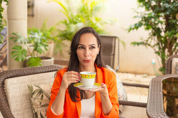 Uma jovem mulher tomando chá quente na varanda da sua casa. Fotografia de meio corpo. - obrazy, fototapety, plakaty